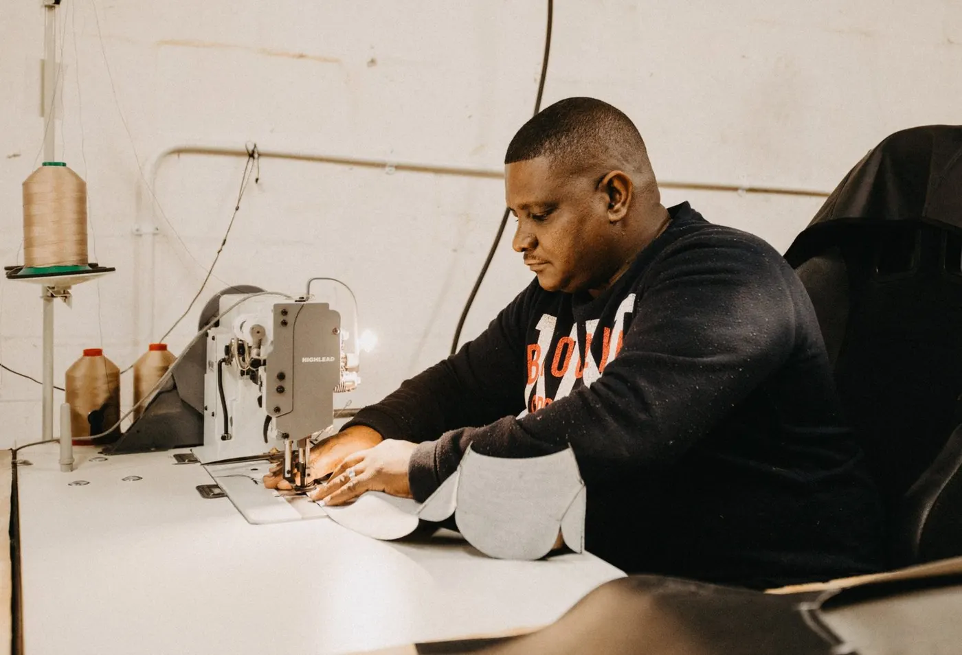 Craftsman stitching leather upholstery at a sewing machine