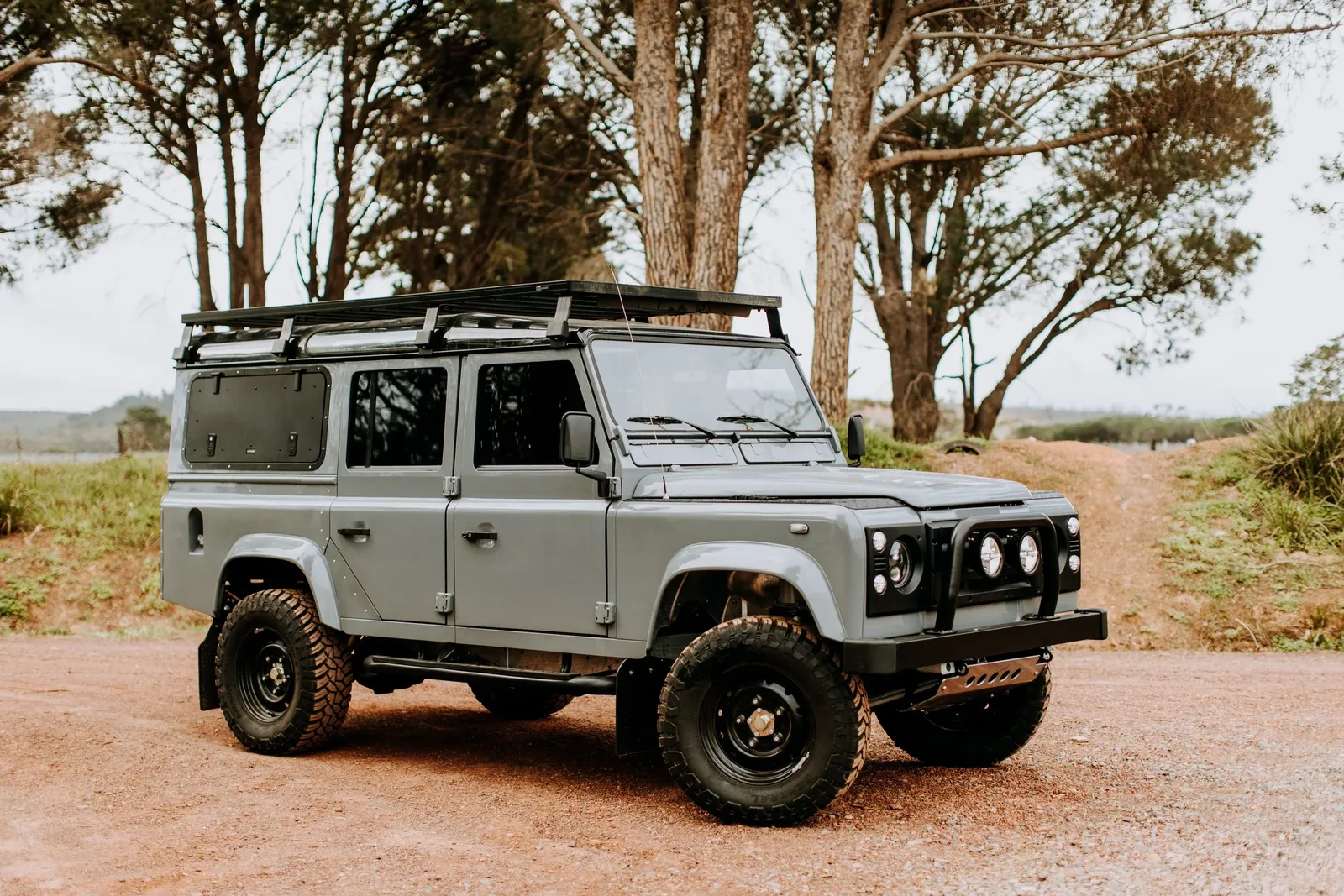 Grey Land Rover Defender 110 station wagon with roof rack, front three-quarter view